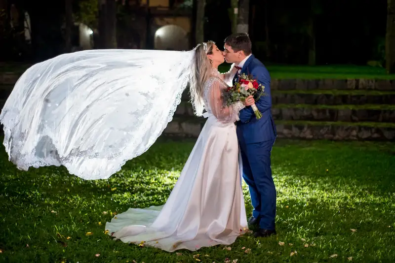 Noivos se beijando com o véu ao vento