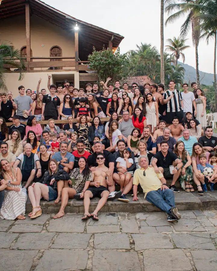 Grupo grande de convidados posando em frente ao casarão