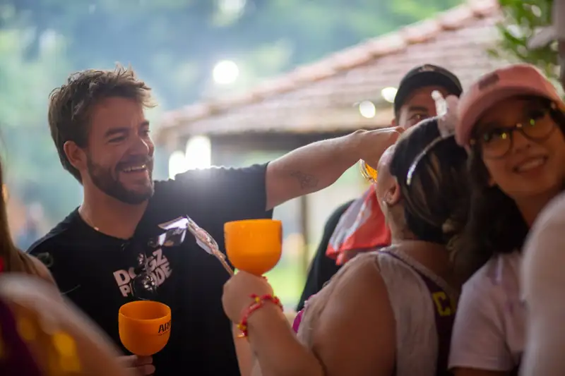 Amigos rindo com copos laranja numa festa à noite