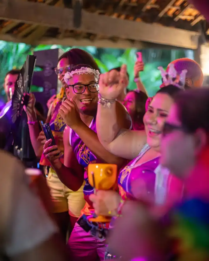 Grupo dançando de copo na mão em festa à noite