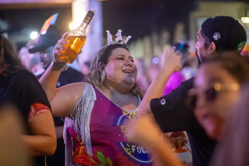Mulher rindo com garrafa levantada na festa