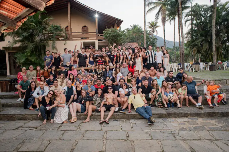 Grupo grande de convidados posando em frente ao casarão