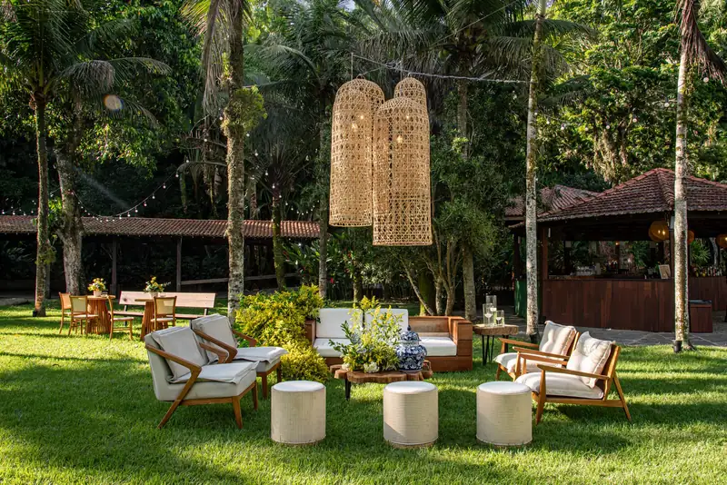 Área de lounge com sofás e luminárias de palha no jardim
