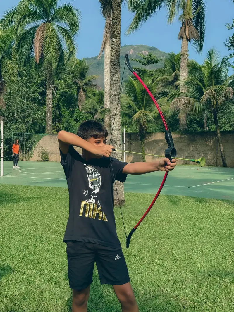 Adolescente praticando tiro com arco no gramado