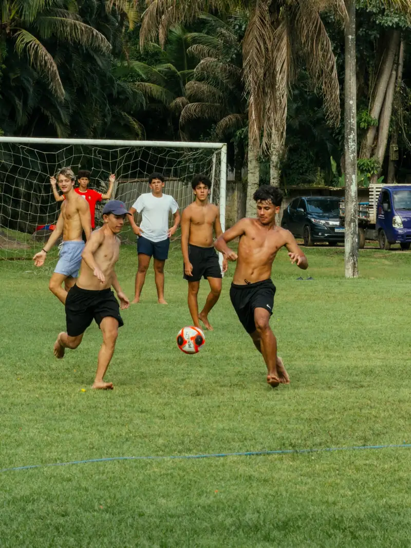 Adolescentes jogando futebol no campo gramado